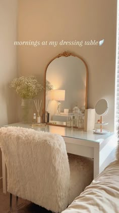 a white desk with a mirror and some flowers