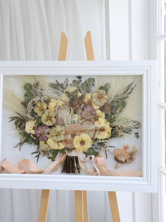 an easel with flowers and feathers on it