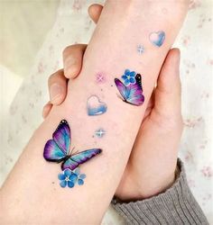 two hands holding each other with tattoos on their fingers and butterflies painted on the wrist