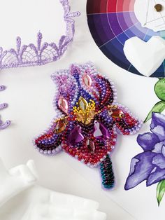 some beads are laying on top of a white surface next to purple and green flowers