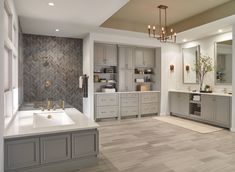 a large bathroom with gray cabinets and white counter tops, along with a chandelier hanging from the ceiling