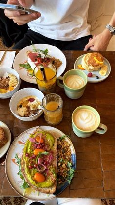 a person sitting at a table with plates of food and drinks in front of them