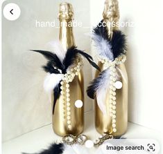 two wine bottles decorated with pearls and feathers