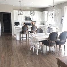 a kitchen and dining room with white cabinets, wood floors and hardwood flooring is shown