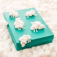 four sheep are sitting on top of a green box with white pom poms