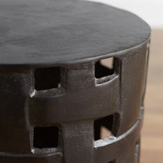 a black table with holes in it on a wooden floor