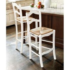 two white chairs sitting on top of a wooden floor next to an island in a kitchen