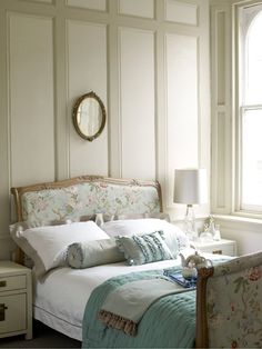 a bedroom with white walls and floral bedding in the corner, along with a mirror on the wall