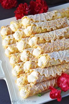 a white plate topped with pastry next to red flowers