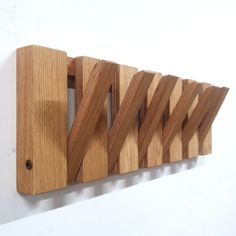 a wooden coat rack with four hooks on it's sides, hanging from the wall