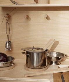 pots and pans are sitting on the counter in front of wooden shelves with utensils