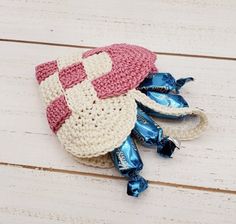 a crocheted hat and candy bag sitting on a wooden table with white boards