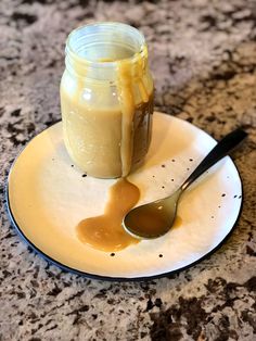 a spoon sitting on top of a white plate next to a jar of peanut butter