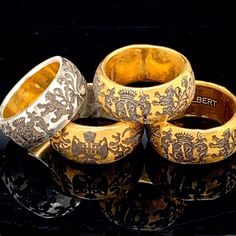 four gold and silver rings sitting on top of a black surface