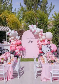 a hello kitty themed birthday party with balloons and tableware set up in front of an arch