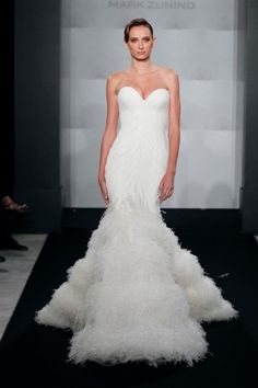 a woman in a white wedding dress on the runway