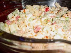 a glass bowl filled with pasta salad on top of a table