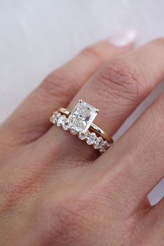 a woman's hand with an engagement ring and diamond set on top of it