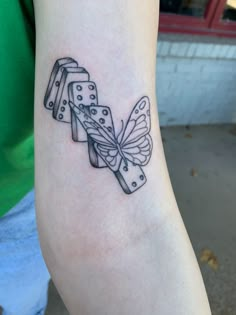 a woman's arm with a butterfly and dominos tattoo on the left forearm