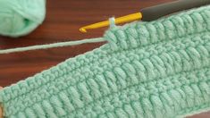 crochet stitches being used to knit the back side of a green piece of yarn