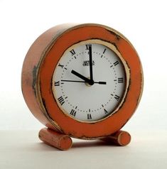 an orange and white clock sitting on top of a wooden stand