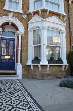 a blue front door and window on a brick building with plants in the potted planters