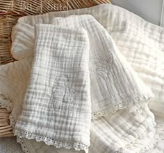 some white towels are sitting in a wicker basket on top of a tablecloth