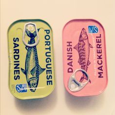 two tins with fish on them sitting next to each other and one has a pair of scissors in it