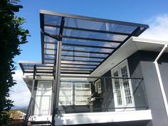 a house with a glass roof and metal railing on the front porch, under a blue sky