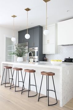 three stools sit at the center of a kitchen island