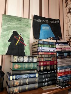 a stack of books sitting on top of a wooden table next to a painting and lamp