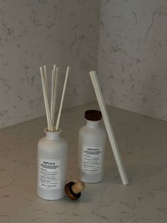 two white bottles with sticks in them sitting on a counter