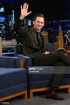 the late show host and actor john krass waves as he sits in his chair