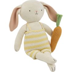 a stuffed rabbit holding a carrot in its hand and wearing overalls, on a white background