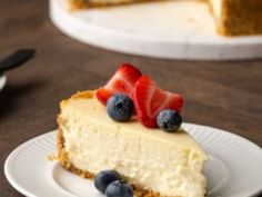 a piece of cheesecake on a plate with strawberries and blueberries in the middle