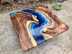 a table made out of wood with blue and brown designs on it, next to a trash can