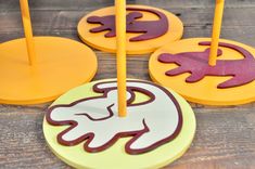 three coasters with candles in the shape of animals on them, one is pink and yellow