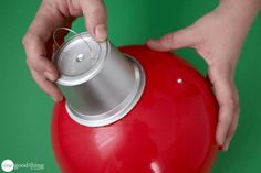 a person is holding a red ball with a can on it and the lid opened