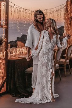 a man and woman standing next to each other in front of a table with candles