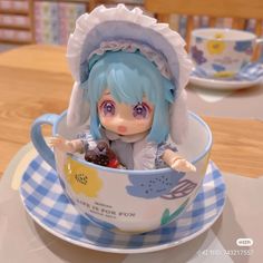 a doll sitting in a teacup on top of a table