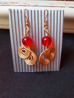 the earrings are made with gold wire and red glass beads