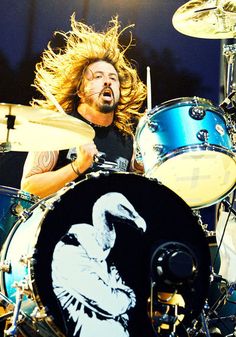 a man with long hair playing drums on stage