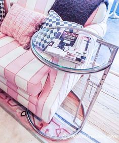 a pink and white couch sitting on top of a wooden floor next to a glass table