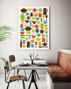 a kitchen table with two chairs and a painting on the wall above it that has teapots in different colors