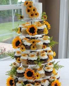 a tiered cake with cupcakes and sunflowers on it