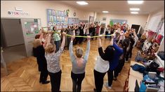 a group of people standing in a room holding up yellow tape with their hands and arms