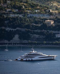 a large white boat floating on top of a body of water next to a hillside