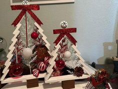 two christmas trees made out of wood with red and white decorations on them, sitting on a table