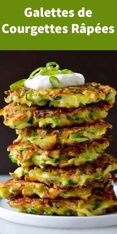 a stack of zucchini fritters on a plate with sour cream and green onions