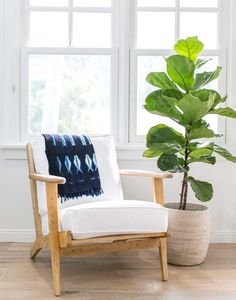 a white chair sitting in front of a window next to a potted green plant